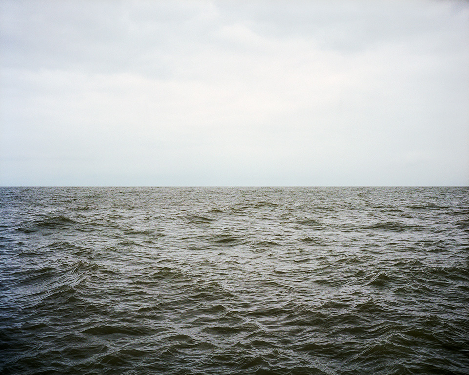 Photograph of small waves in water stretching to the horizon